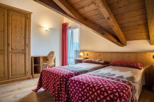 1 Schlafzimmer mit 2 Betten in einem Zimmer mit Holzdecken in der Unterkunft Giongo Residence Aparthotel 201 in Lavarone