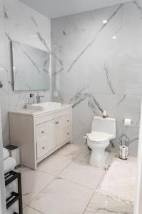 Baño blanco con lavabo y aseo en Hummingbird Oceanfront Cottage, en Hauula