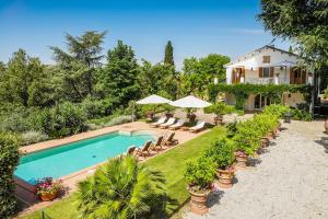 a pool with chairs and umbrellas in front of a house at Villa dei Limoni in Ripatransone
