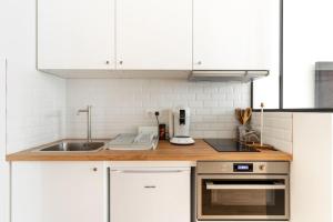 una cocina con armarios blancos y fregadero en Trocadéro/Victor Hugo : Luxury Apartment 1BR-4P, en París