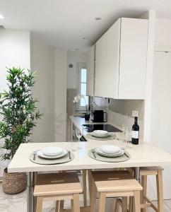 une cuisine blanche avec une table avec des assiettes et des verres à vin dans l'établissement PERGO, à Paris