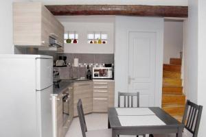a kitchen with a table and a white refrigerator at Gite les coquelicots ( classé 2* ) Duplex in LʼIsle-sur-la-Sorgue