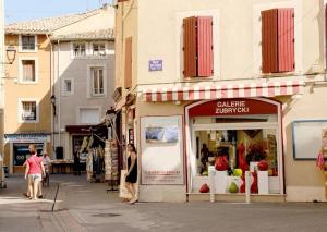 a woman standing in front of a store on a street at Gite les coquelicots ( classé 2* ) Duplex in LʼIsle-sur-la-Sorgue