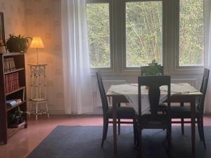 a dining room with a table and chairs and two windows at Officersvillorna, Älvkarleby Vandrarhem in Älvkarleby