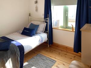 a bedroom with a bed with blue curtains and a window at No2 The Neuk in Belford