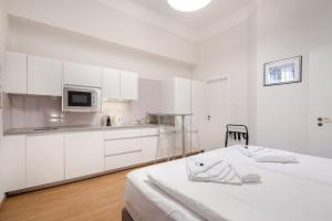 een witte keuken met witte kasten en een bed bij Klauzál Garden City Apartments- Studio K31 in Boedapest