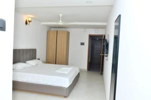 a bedroom with a white bed and a sliding door at SWAGATH RESIDENCY in Devarkonda