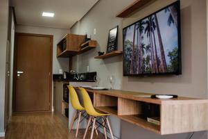 a kitchen with a bar with yellow chairs and a television on the wall at Loft divino no Parque Una in Pelotas