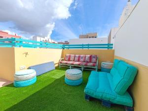 a balcony with a couch and stools on a roof at Daydream Medano Coliving in El Médano