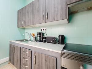 a kitchen with wooden cabinets and a sink at Daydream Medano Coliving in El Médano