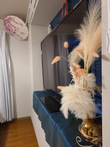 a vase with feathers on a table next to a tv at 美ハウス in Tokyo