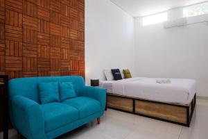 ジョグジャカルタにあるUrbanview Griya Kusumo Seturan Yogyakartaのベッドと青いソファのある寝室
