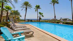 una piscina con 2 sillas y palmeras en Casa Curacao Ocean Resort near Mambo Beach, en Willemstad