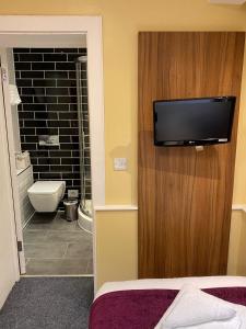 a bathroom with a toilet and a television on a wall at City Continental London Kensington in London