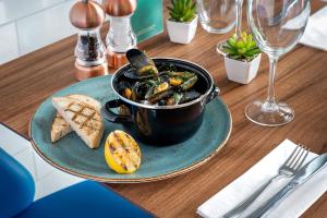 a table with a bowl of food on a plate with bread at Courtyard by Marriott Glasgow Airport in Paisley