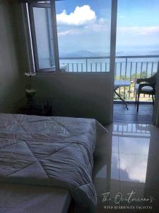 a bedroom with a bed with a view of the ocean at Taal View Condo by Liza in Tagaytay