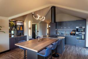 una cocina con una gran mesa de madera y armarios azules en The Deerview Stables, en Bonvilston