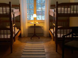 a room with bunk beds and a table with a lamp at Officersvillorna, Älvkarleby Vandrarhem in Älvkarleby