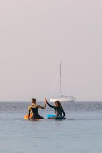 dos personas en el agua con un velero en el océano en Laguna Beach Family Camps Öland en Mörbylånga