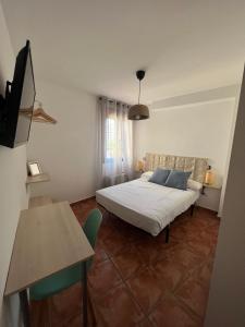 1 dormitorio con cama, mesa y TV en Hostal Corper Navalcarnero, en Navalcarnero