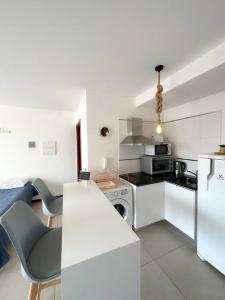 uma cozinha branca com um fogão e um micro-ondas em Hermoso Loft en zona Shopping Sol 01 em Assunção