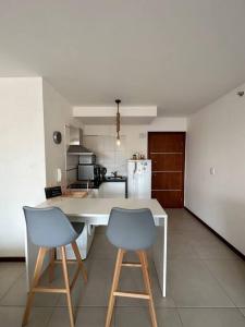 uma cozinha com duas cadeiras azuis e uma mesa branca em Hermoso Loft en zona Shopping Sol 01 em Assunção