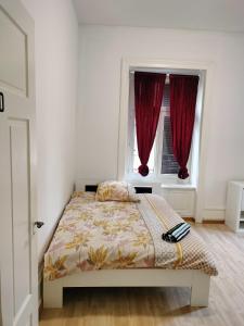 a bedroom with a bed and two windows with red curtains at City Home Zurich in Zürich