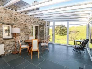 a dining room with a stone wall and a table and chairs at Garth Morthin The Stables in Morfa Bychan