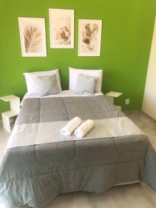 1 dormitorio verde con 1 cama grande y 2 almohadas en Casa de vidro com vista para a Mata Atlântica no Centro de Miguel Pereira, en Miguel Pereira