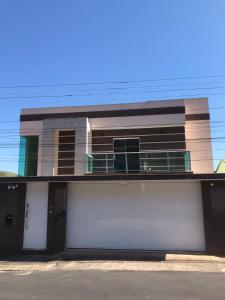 ein Haus mit einer weißen Garage und einem Balkon in der Unterkunft Casa de vidro com vista para a Mata Atlântica no Centro de Miguel Pereira in Miguel Pereira