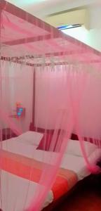 - une chambre avec un lit recouvert de rideaux roses dans l'établissement House of Rose, à Dodanduwa