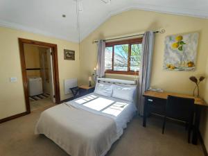 een slaapkamer met een bed, een bureau en een raam bij Swiss Cottage Guest House in Kaapstad