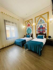 a hotel room with two beds with blue sheets at Jumadaler Дворец эмира в старом городе in Bukhara