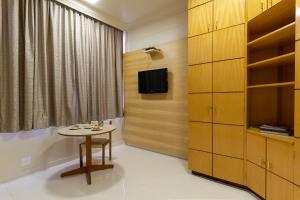 a room with a table and a tv and a cabinet at Uberaba Hotel Suítes in Uberaba