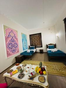 a room with two beds and a table with food on it at Jumadaler Дворец эмира в старом городе in Bukhara