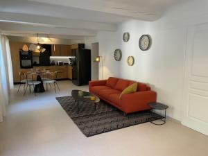 sala de estar con sofá rojo y cocina en Bastide De Charme Sud Luberon, en Saint-Martin-de-la-Brasque