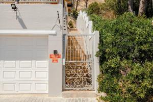 a white fence with a gate next to a house at The Grosvenor Guest House in Simonʼs Town