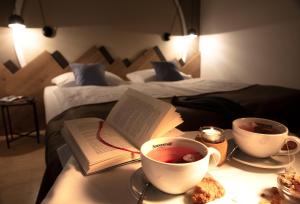 a table with two cups of tea and a book at JUFA Hotel Wipptal in Steinach am Brenner