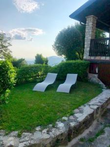 two white benches sitting in the grass near a house at Casa Emy in Adrara San Rocco