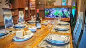 - une table avec des assiettes, des verres à vin et un aquarium dans l'établissement Villa Panoramica - 200Mq - SPA - Giardino Privato - 0039-34893-66818, à Aoste