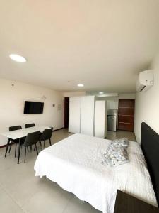 a bedroom with a white bed and a table with chairs at Hermoso Loft Zona Shopping Sol 02 in Asuncion