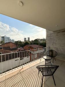a balcony with two chairs and a train on it at Hermoso Loft Zona Shopping Sol 02 in Asuncion