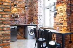 a kitchen with a brick wall and a table with chairs at HOUSEHOST ApartmenI: Podbrzezie 2/20 in Krakow