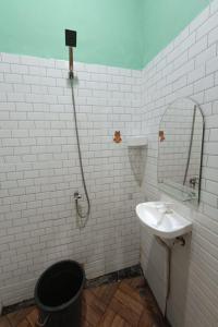 La salle de bains blanche est pourvue d'un lavabo et d'un miroir. dans l'établissement OYO Life 93158 Kost Asaka, à Serang