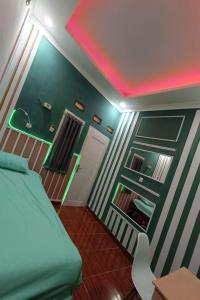 Cette chambre comprend un lit vert et un éclairage rose. dans l'établissement OYO Life 93158 Kost Asaka, à Serang