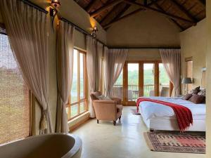 1 dormitorio con cama, bañera y ventanas en Reedbuck Lodge @Cyferfontein in Mabalingwe Reserve, en Bela-Bela