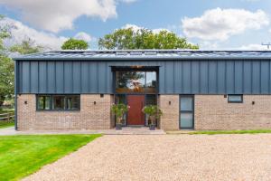 a brick house with a red door at Old Harrow Barn by Bloom Stays in Ashford