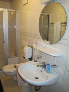 een badkamer met een wastafel, een toilet en een spiegel bij Gasthaus Adler in Wangen im Allgäu