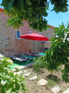 a patio with a red umbrella and lounge chairs at Casa Virginia in Ouzenda