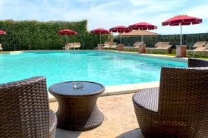 a swimming pool with chairs and a table and umbrellas at Hotel Villa Tirreno in Tarquinia